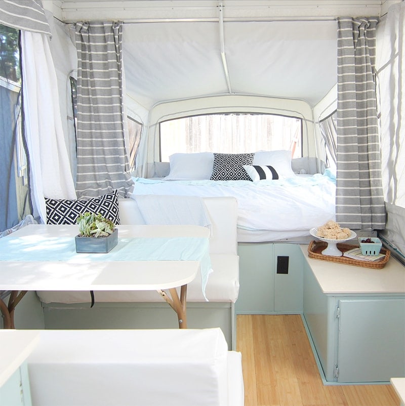 light and fresh camper remodel with light blue cabinets, white countertops and neutral cushions
