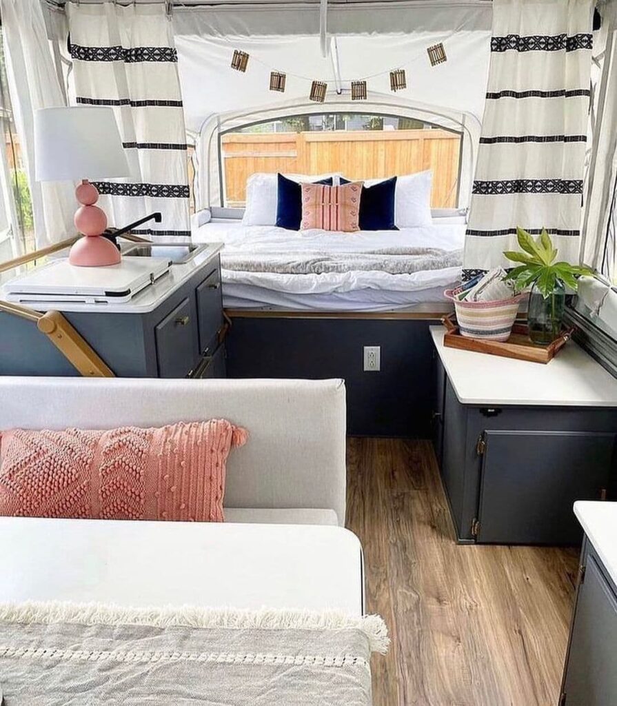 pop up camper remodel with dark blue cabinets, pink accents and neutral bedding