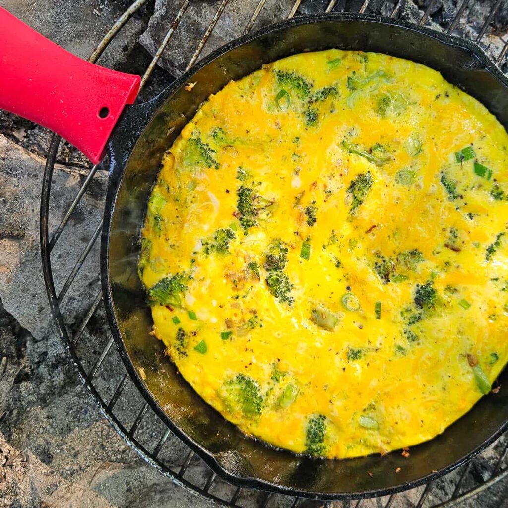 egg camping breakfast in cast iron skillet frittata with broccoli, onion and cheese