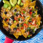 camping nachos made over the campfire in cast iron or aluminum foil pan
