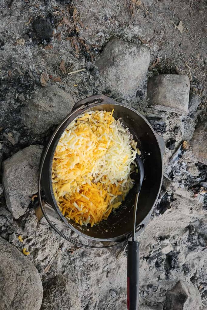 dutch oven macaroni and cheese with ground beef cooked in one pot over the campfire