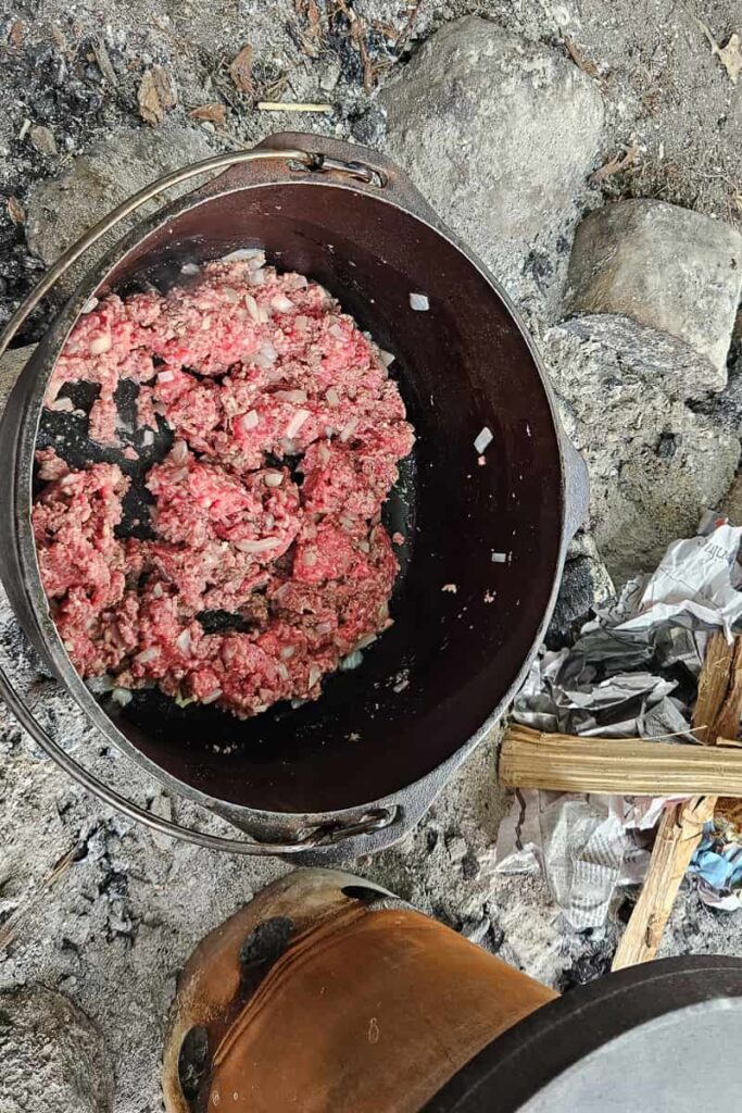 ground beef in cast iron dutch oven over the campfire