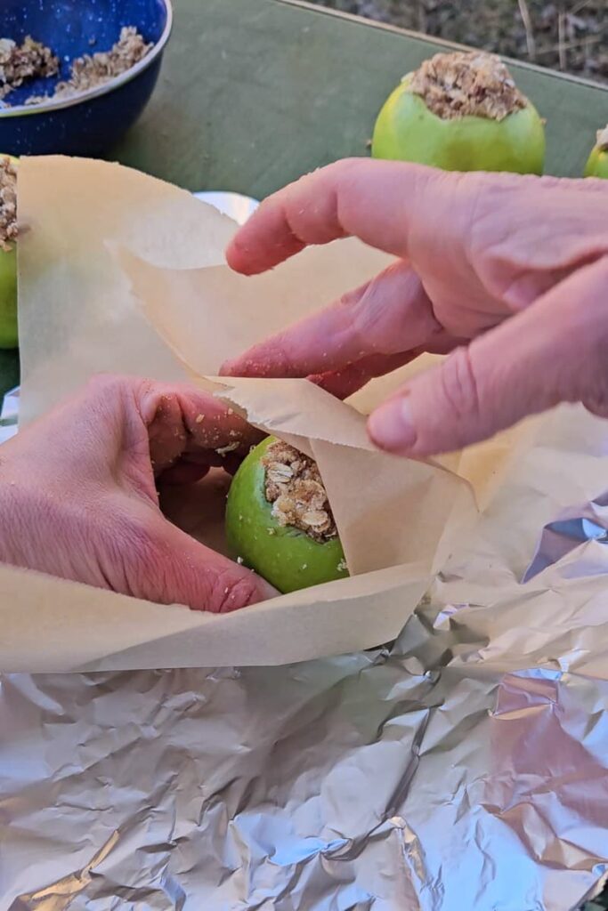 wrap apples in parchment paper and foil and cook over the fire to make baked apples