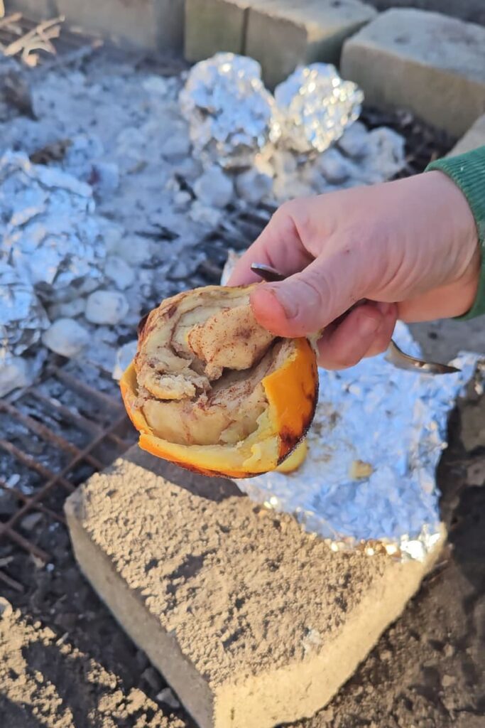 cook cinnamon rolls over the campfire in an orange peel