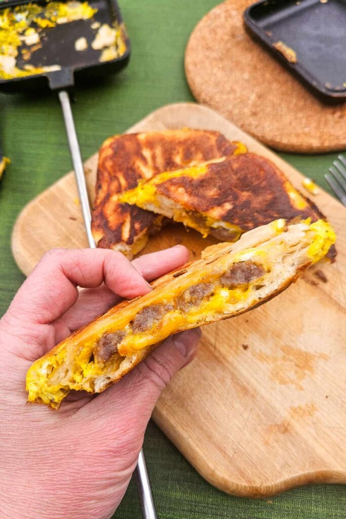 camping breakfast recipe with biscuits, sausage egg and cheese in hobo pie cooked in pie iron over campfire