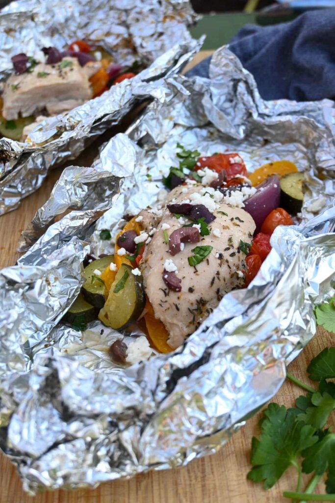 greek chicken foil packet on campfire with zucchini, tomatoes, olives, peppers, feta