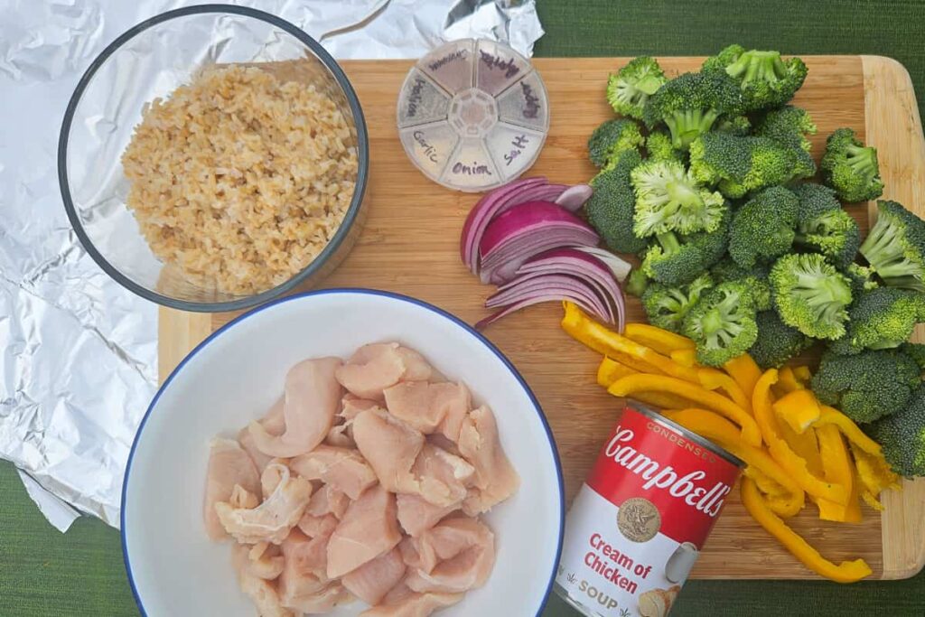 ingredients in campfire foil packet dinner with chicken, broccoli, rice, peppers, onion and cream of chicken soup