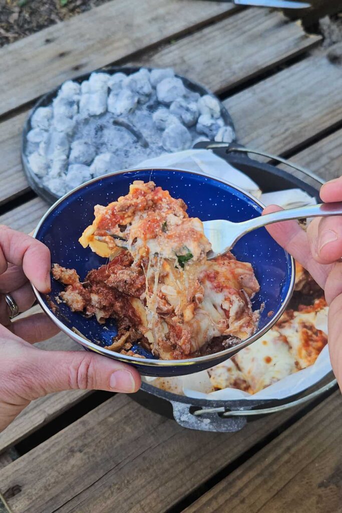 camping lasagna cooked over the campfire in a dutch oven for family or scout camping trip
