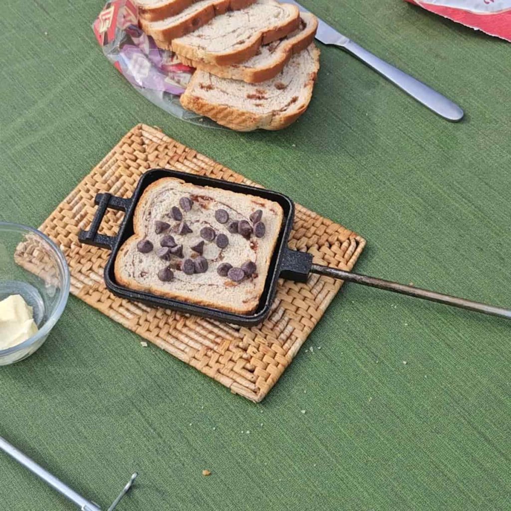 steps to make campfire hobo pie dessert with chocolate and cherries over the campfire in a pie iron