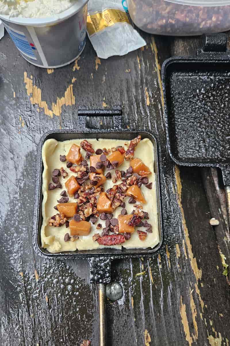 caramel, chocolate, cream cheese and pecans in pie crust in hobo pie dessert